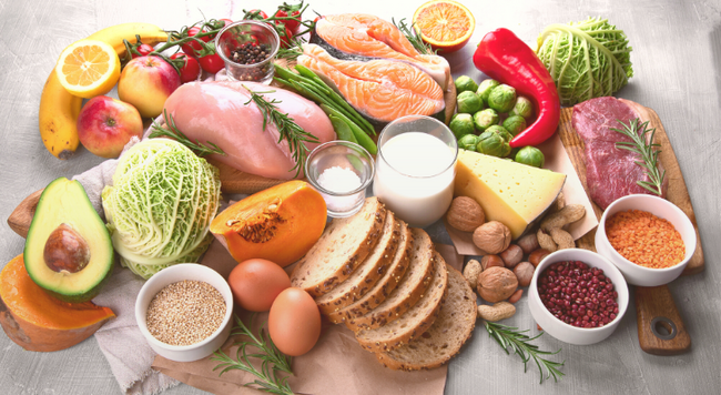 Image of meats, fruits, vegetables, and grains on a cutting board